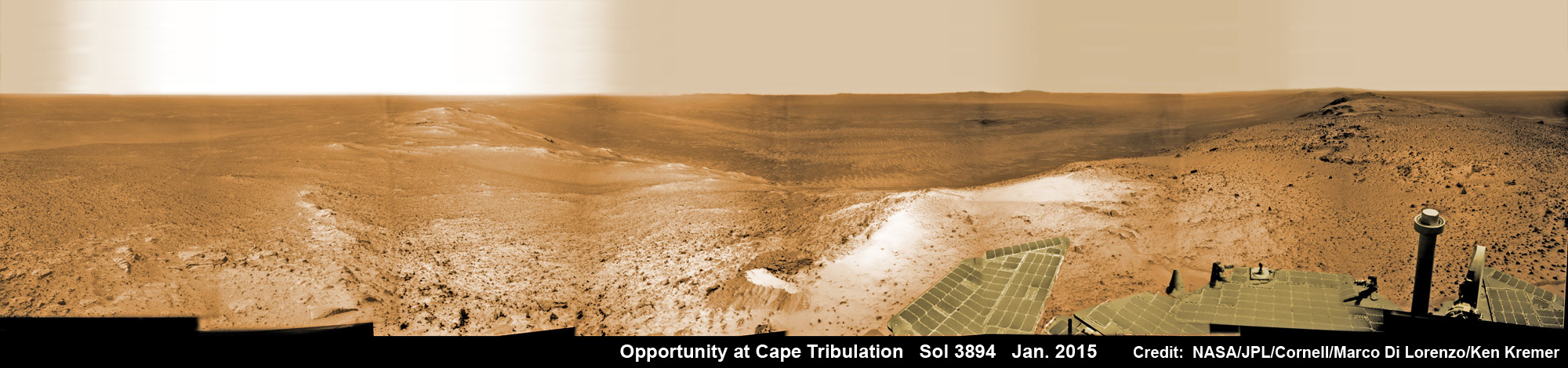 Stunning new mountain top view from NASA’s Opportunity rover after reaching summit of Cape Tribulation in January 2015 nearly eleven years after Martian touchdown.  Panoramic scene shows vast expanse of Endeavour Crater from highest mountain rover will ever climb. See rover solar panels at right and wheel tracks at left.  This navcam camera photo mosaic was assembled from images taken on Sol 3894, Jan. 6, 2015 and colorized.  Credit: NASA/JPL/Cornell/ Marco Di Lorenzo/Ken Kremer - kenkremer.com