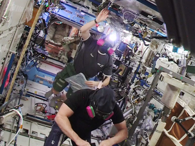From NASA TV: "Astronauts Barry WiImore (foreground) and Terry Virts re-entered the U.S. segment wearing protective masks." Image Credit: NASA TV
