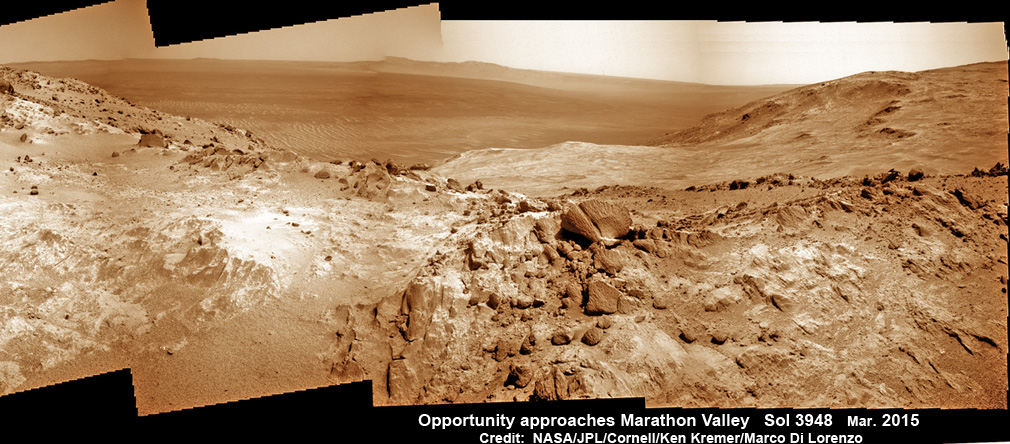 NASA’s Opportunity Rover scans along a spectacular overlook towards Marathon Valley on March 3, 2015 showing flat-faced rocks exhibiting a completely new composition from others examined earlier.  Marathon Valley and Martian cliffs on Endeavour crater hold deposits of water altered clay minerals.  This navcam camera photo mosaic was assembled from images taken on Sol 3948 (March 3, 2015) and colorized.  Credit: NASA/JPL/Cornell/Ken Kremer/kenkremer.com/Marco Di Lorenzo/Ken Kremer/kenkremer.com