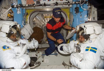 Bill Oefelein (center) works inside the Quest airlock to prepare Bob Curbeam (left) and Christer Fuglesang for their EVAs. Photo Credit: NASA