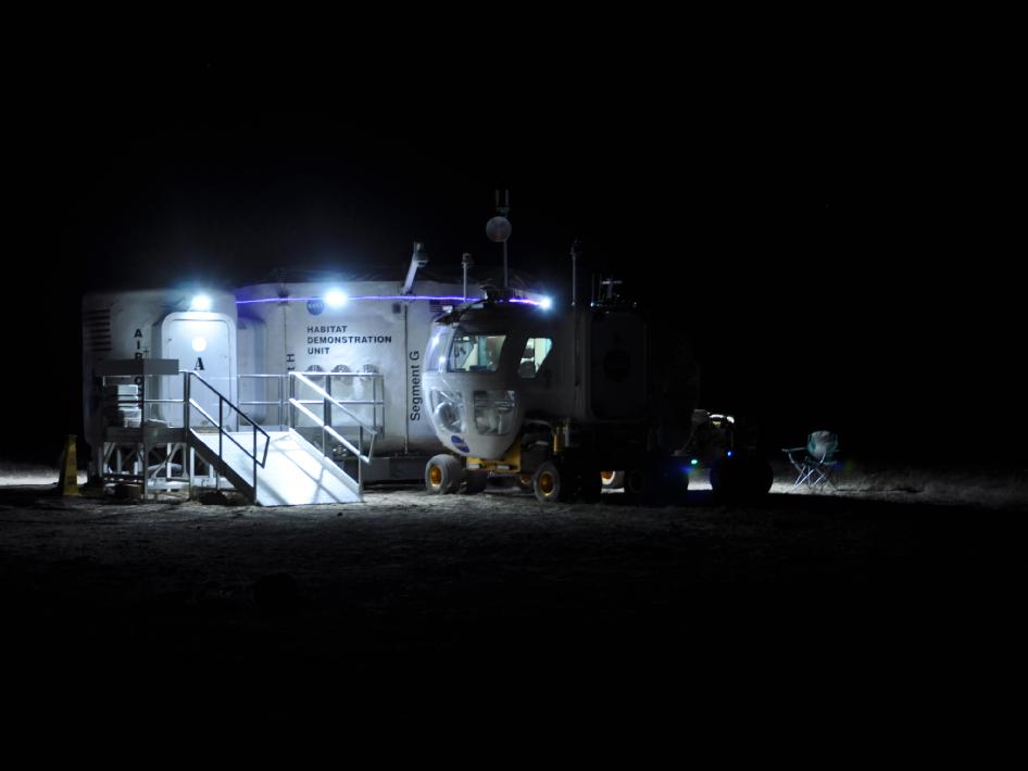 A view of the space habitat at night, docked with the Space Exploration Vehicle. This photo was taken during the 2010 Desert RATS field testing, from Aug. 31 - Sept. 15, 2010, in Black Point Lava Flow, Ariz. Image credit: NASA