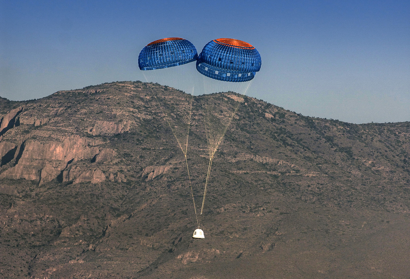 After a clean separation from the propulsion module, the New Shepard crew capsule descends to a gentle landing in the west Texas desert.  Credit: Blue Origin
