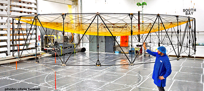 A 9-meter AstroMesh reflector deployed for testing at the Goleta lab with Astro Aerospace engineer Dan Ochoa looking on. Photo Credit: Chris Howell / AmericaSpace