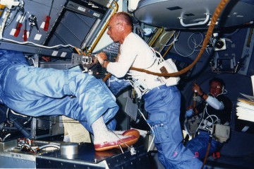 Taylor Wang's legs emerge from the Drop Dynamics Module (DDM) as Bill Thornton assists him with his experiment. Photo Credit: NASA, via Joachim Becker/SpaceFacts.de