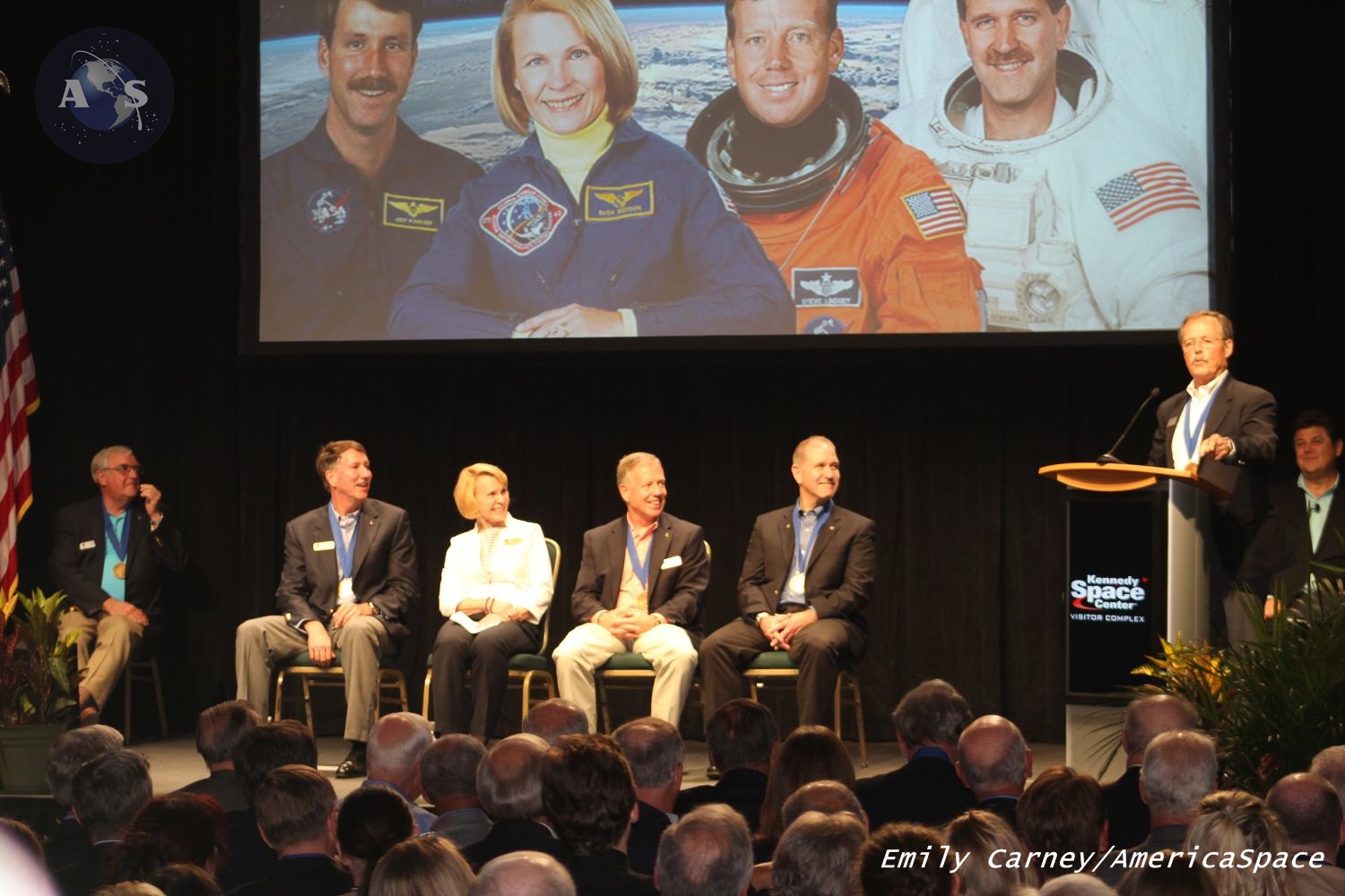 Astronaut Robert "Hoot" Gibson (at podium) speaks prior to Dr. Rhea Seddon's induction into the U.S. Astronaut Hall of Fame on Saturday, May 30th. From left: Astronaut Scholarship Foundation Chairman Daniel Brandenstein, Kent Rominger, Seddon, Steve Lindsey, John Grunsfeld, Gibson, and CNN's John Zarrella. Photo Credit: Emily Carney / AmericaSpace