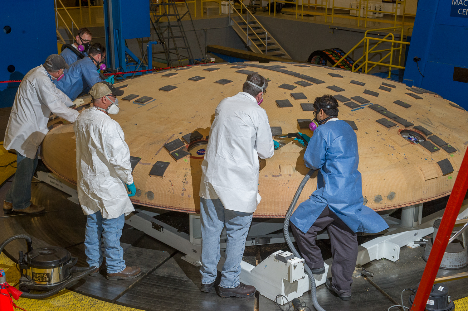Engineers from NASA's Ames Research Center in Moffett Field, California, and NASA's Marshall Space Flight Center in Huntsville, Alabama, remove segments of a heat-resistant material called Avcoat from the surface of the Orion heat shield, the protective shell designed to help the next-generation crew module and its future occupants withstand the heat of atmospheric reentry. The work is being conducted in the seven-axis milling machine facility at Marshall. Photo Credits: NASA/MSFC/Emmett Given