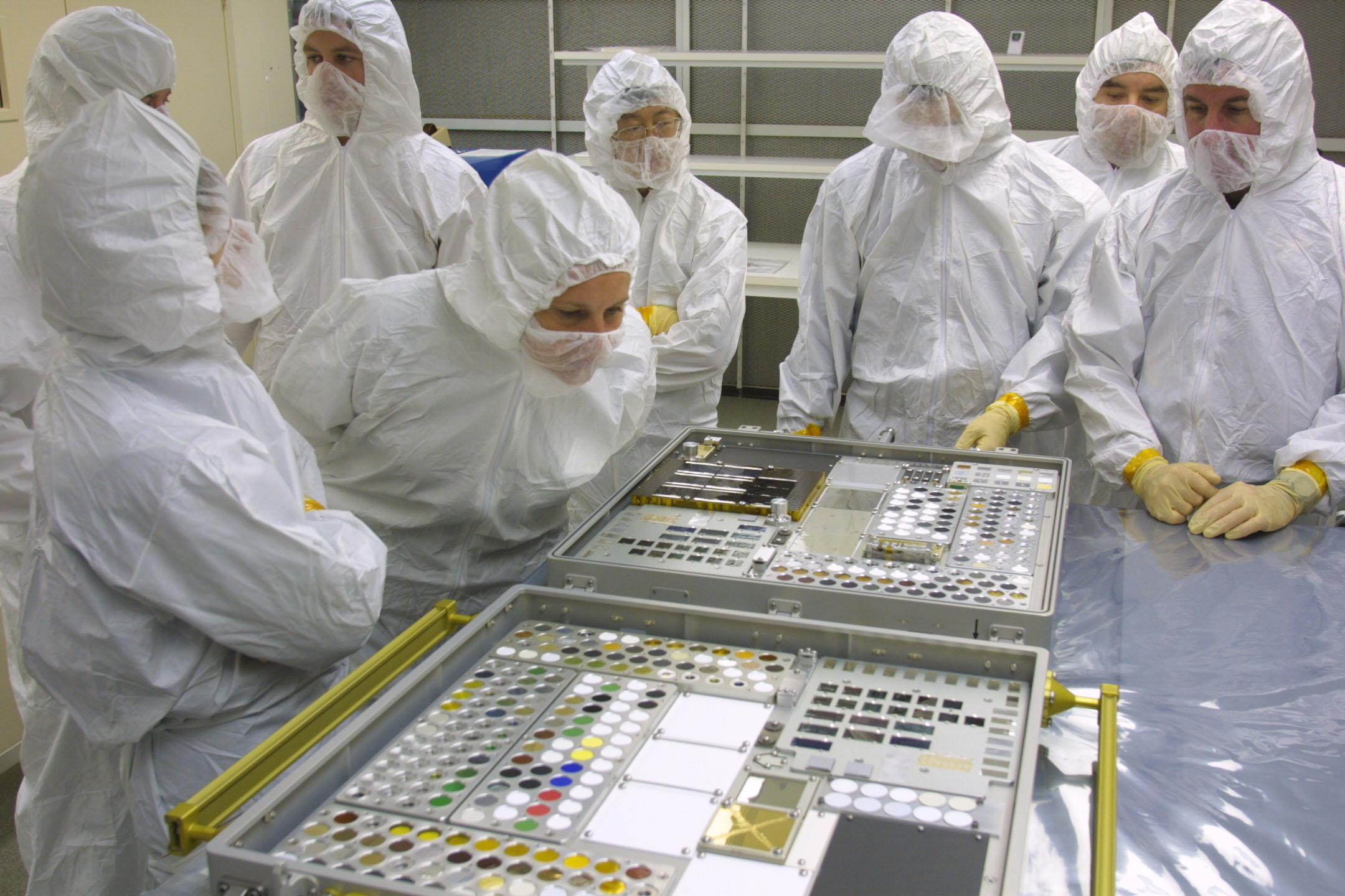 Astronauts and Langley Research Center investigators illustrate hardware scale as they examine two MISSE experiment cases later flown to the ISS. Photo Credit NASA