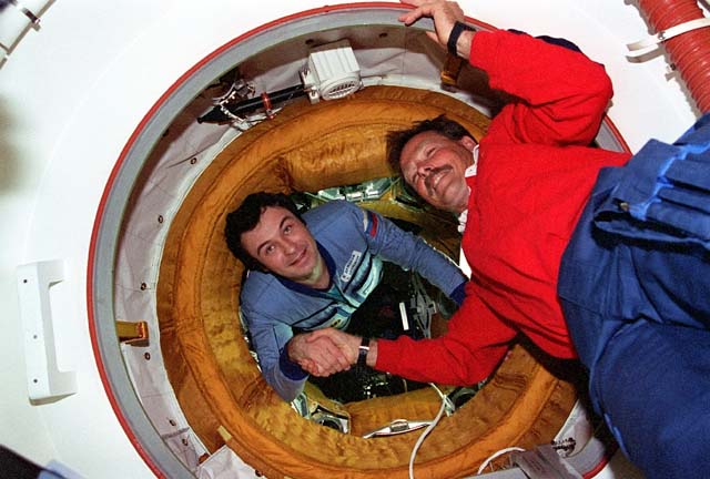 Mir Commander Vladimir Dezhurov (left) and STS-71 Commander Robert "Hoot" Gibson shake hands after hatch opening on 29 June 1995. Photo Credit: NASA