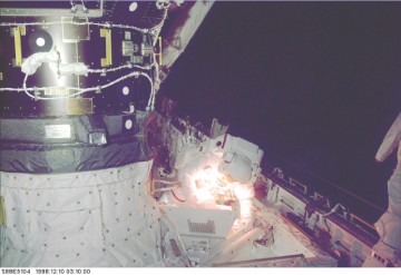 Jerry Ross works near the Pressurized Mating Adapter (PMA) during orbital darkness. He is utilizing his helmet lights for illumination. Photo Credit: NASA