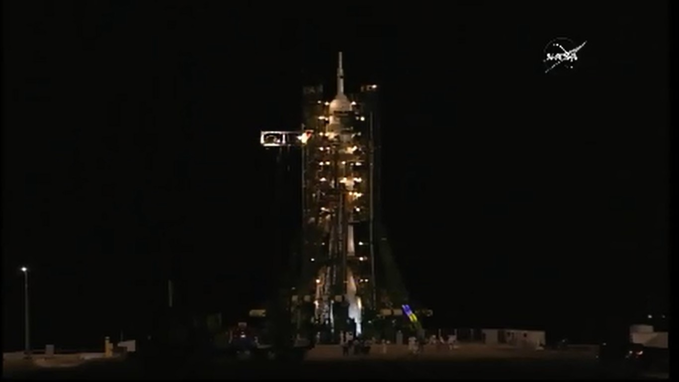 Encapsulated by its supporting structures, the Soyuz-FG booster is readied for launch as night falls over Baikonur. Photo Credit: NASA TV