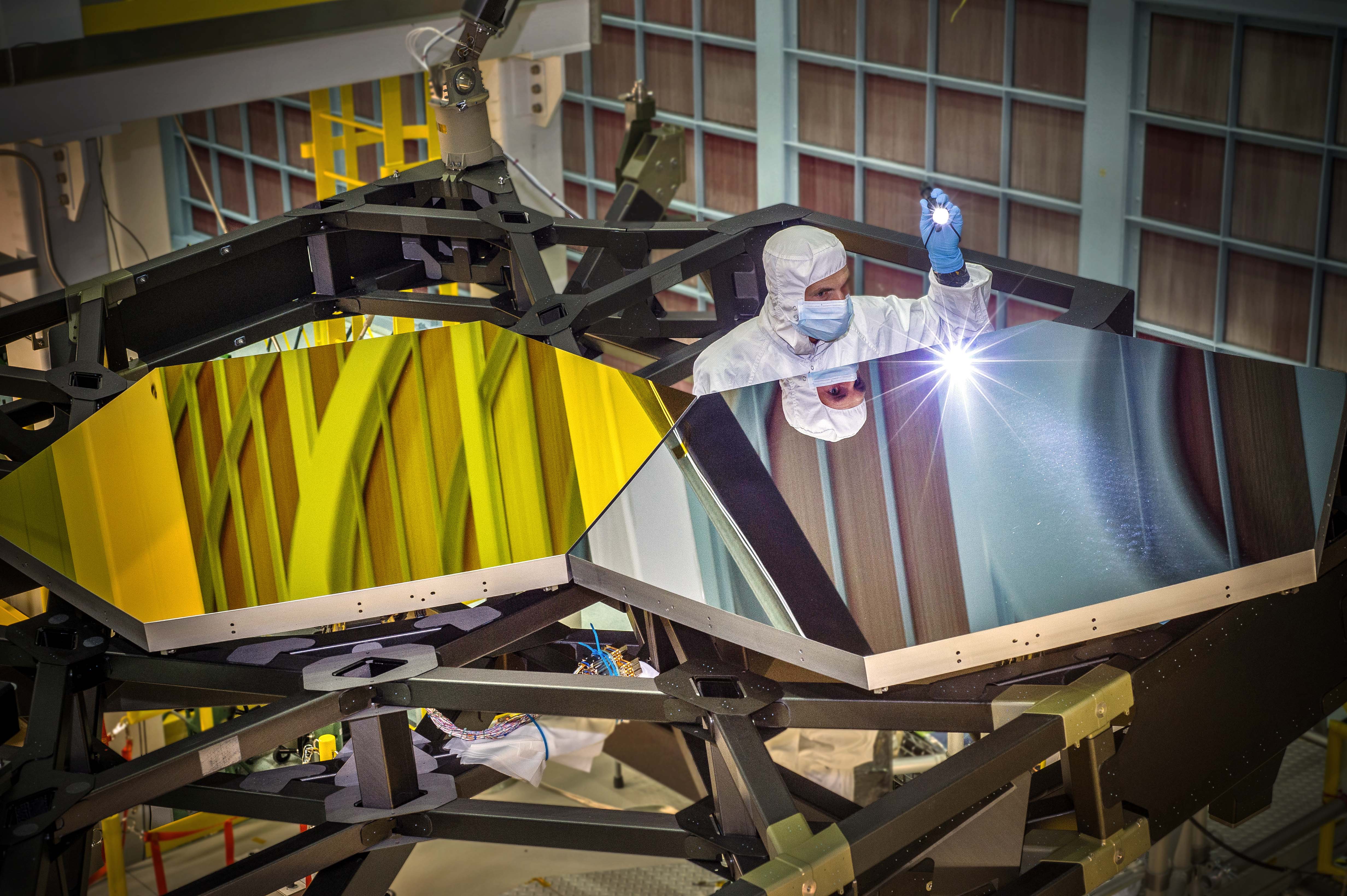 From ESA: "This image shows two polished test mirror segments being inspected by an optical engineer: one segment with the gold coating already applied, the other without. In the meantime, the coating of all 18 mirrors has been completed." Photo Credit: NASA/C. Gunn
