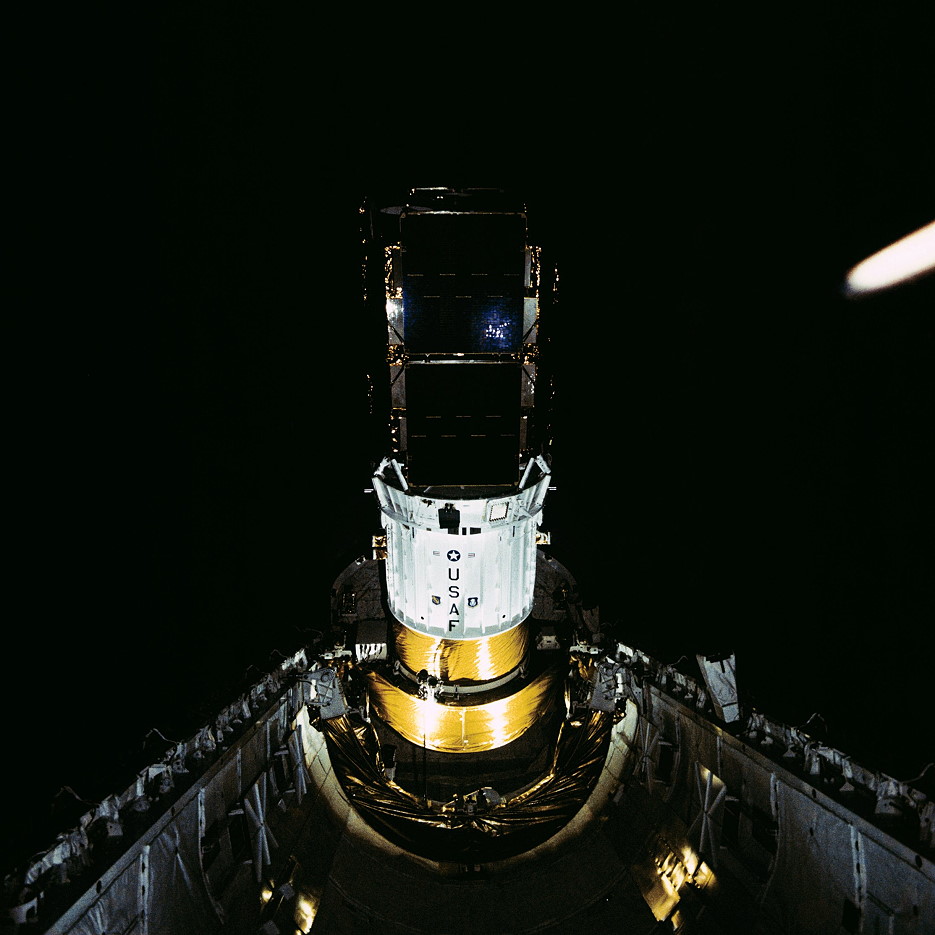 The twin Defense Satellite Communications System (DSCS)-III satellites are clearly visible, atop their Inertial Upper Stage (IUS), during deployment operations. This and other images were finally declassified in the summer of 1998, some 13 years after Mission 51J. Photo Credit: NASA, via Joachim Becker/SpaceFacts.de