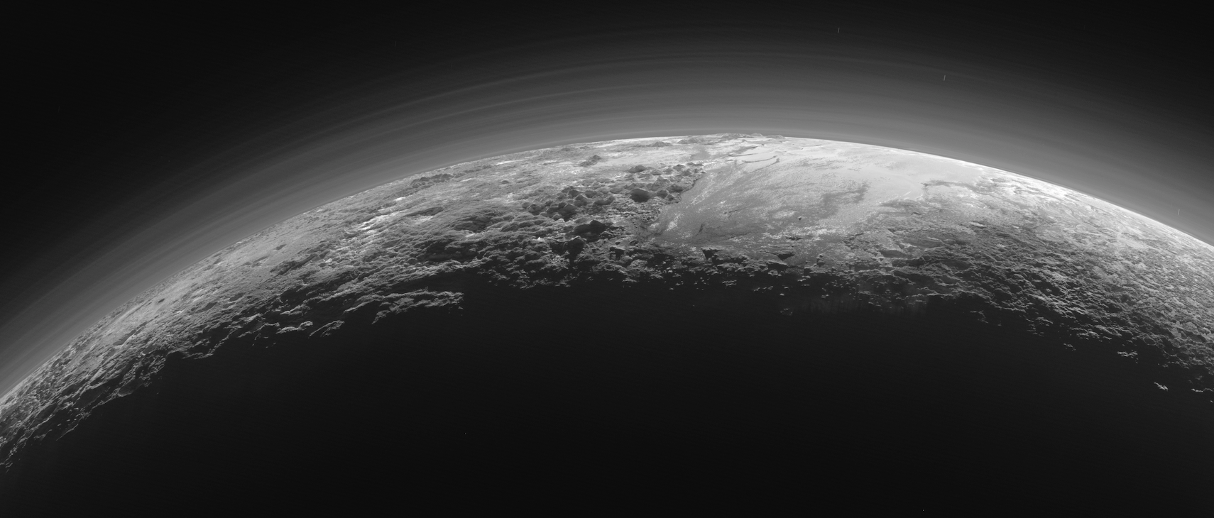 Stunning new panorama of Pluto backlit by the Sun, showing the icy plains, rugged mountains and hazes in the atmosphere. Image Credit: NASA/JHUAPL/SwRI