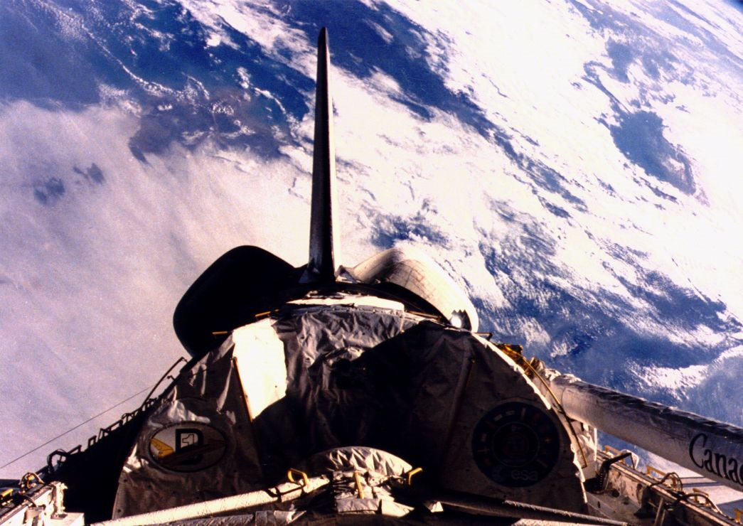 In one of the final views of Challenger in space, the orbiter sails over the cloud-bedecked Earth, with the Spacelab D-1 module clearly visible in her payload bay. Photo Credit: NASA, via Joachim Becker/SpaceFacts.de