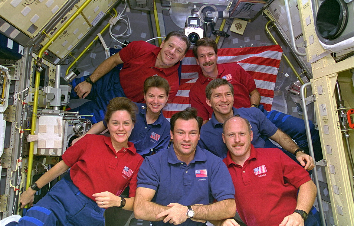 Clad in their respective "red" and "blue" shifts, to denote their membership of the 12-hour Red and Blue Teams, the STS-73 crew pose for an in-flight portrait in the Spacelab module. Front row (from left) are Kathy Thornton, Mike Lopez-Alegria and Ken Bowersox, with Catherine "Cady" Coleman and Fred Leslie in the middle row and Al Sacco and Kent Rominger bringing up the rear. Photo Credit: NASA