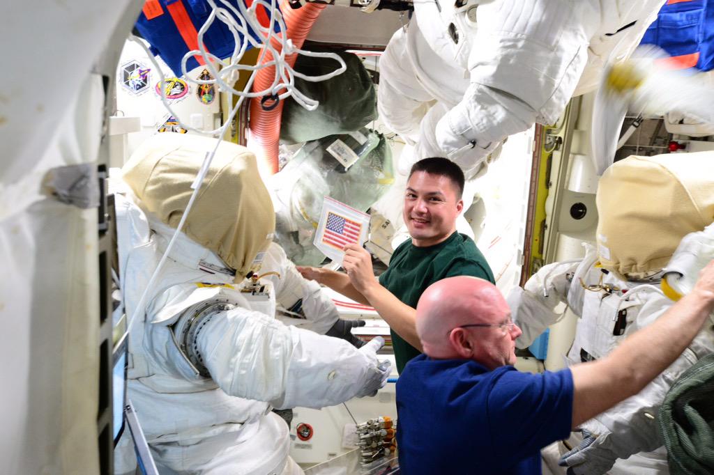 Kjell Lindgren (background) and Scott Kelly check out their Extravehicular Mobility Units (EMUs) in the Quest airlock, ahead of EVAs 32 and 33. Photo Credit: NASA/Twitter