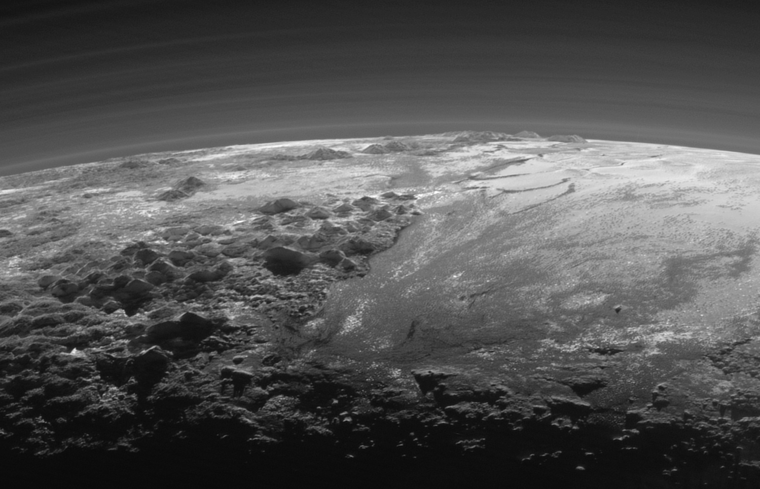 Perspective view of Pluto, showing the ice mountains and glacier-like plains, as well as haze layers in the atmosphere. Image Credit: NASA/JHUAPL/SwRI)