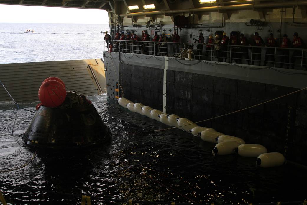 NASA’s Orion spacecraft is pulled safely into the well deck of the U.S. Navy’s USS Anchorage, following its splashdown in the Pacific Ocean. Caption and Credit: NASA 