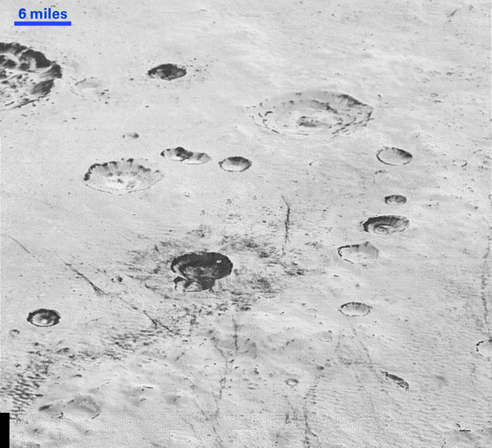 View of rugged, cratered icy plains on Pluto. Layering can also be seen inside the walls of the craters. Image Credit: NASA/JHUAPL/SwRI