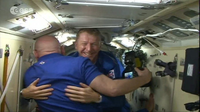Expedition 46 Commander Scott Kelly and incoming Soyuz TMA-19M crewman Tim Peake share greetings, shortly after hatch-opening. Photo Credit: ESA