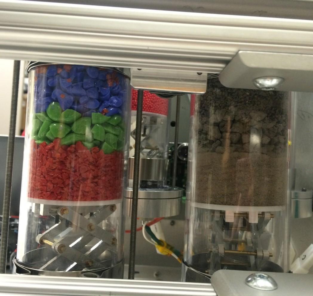 A view of the contents of two of Strata-1's tubes. The regolith simulant on the left is a simplified model consisting of angular fragments of colored glass, sorted into three sizes. The tube on the right contains pulverized meteorite material to closely resemble the actual regolith on a small asteroid, also sorted into three sizes. Credits: NASA 
