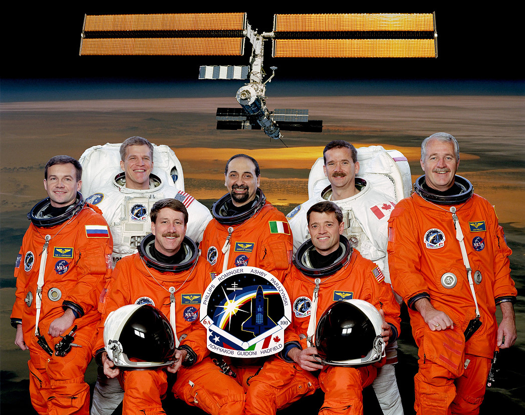 The multi-national STS-100 crew comprised, in orange suits, from left, Yuri Lonchakov, Kent Rominger, Umberto Guidoni, Jeff Ashby and John Phillips, and in white EVA suits Scott Parazynski (left) and Chris Hadfield. Photo Credit: NASA, via Joachim Becker/SpaceFacts.de