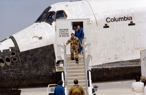 Commander John Young descends the steps from Columbia, as Bob Crippen (at the foot of the stairs) looks on. Photo Credit: NASA