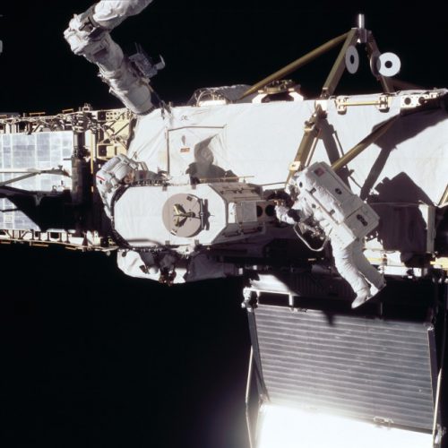 Dan Barry and Pat Forrester work to install the Early Ammonia Servicer (EAS) during EVA-1. The EAS can be clearly seen at the center of the image. Photo Credit: NASA