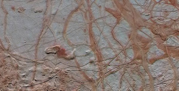 The surface of Europa. Darker "stains" in cracks are thought to be residue from material which come up to the surface from the ocean below. Image Credit: NASA/JPL-Caltech/ SETI Institute
