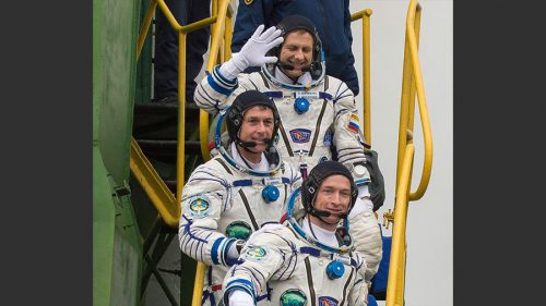 Clad in their Sokol ("Falcon") launch and entry suits, the Soyuz MS-02 crew wave to wellwishers before boarding their spacecraft at Baikonur’s Site 31. From top to bottom are Andrei Borisenko, Shane Kimbrough and Sergei Ryzhikov. Photo Credit: NASA
