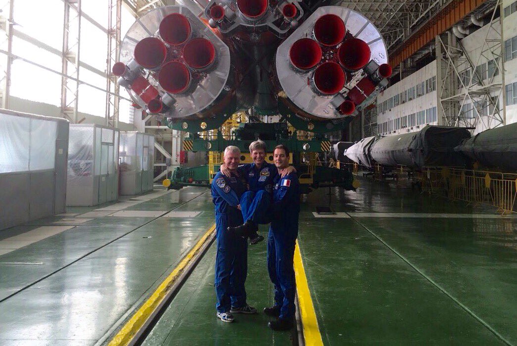 Demonstrating the need to mutually "support" one another, Oleg Novitsky (left) and Thomas Pesquet cradle Peggy Whitson, as their Soyuz-FG booster undergoes final preparation behind them. Photo Credit: NASA/Peggy Whitson/Twitter
