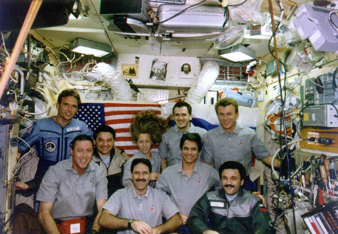 The STS-81 and Mir crews gather for a group portrait in the space station's base block. Front row, from left, are Mike Baker, John Grunsfeld, John Blaha and Aleksandr Kaleri. Back row, from left, are Jerry Linenger, Valeri Korzun, Marsha Ivins, Jeff Wisoff and Brent Jett. Photo Credit: NASA, via Joachim Becker/SpaceFacts.de 