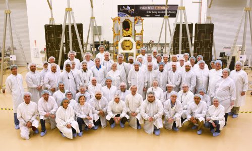 Iridium NEXT engineers pose with their satellites. Photo credit: Iridium