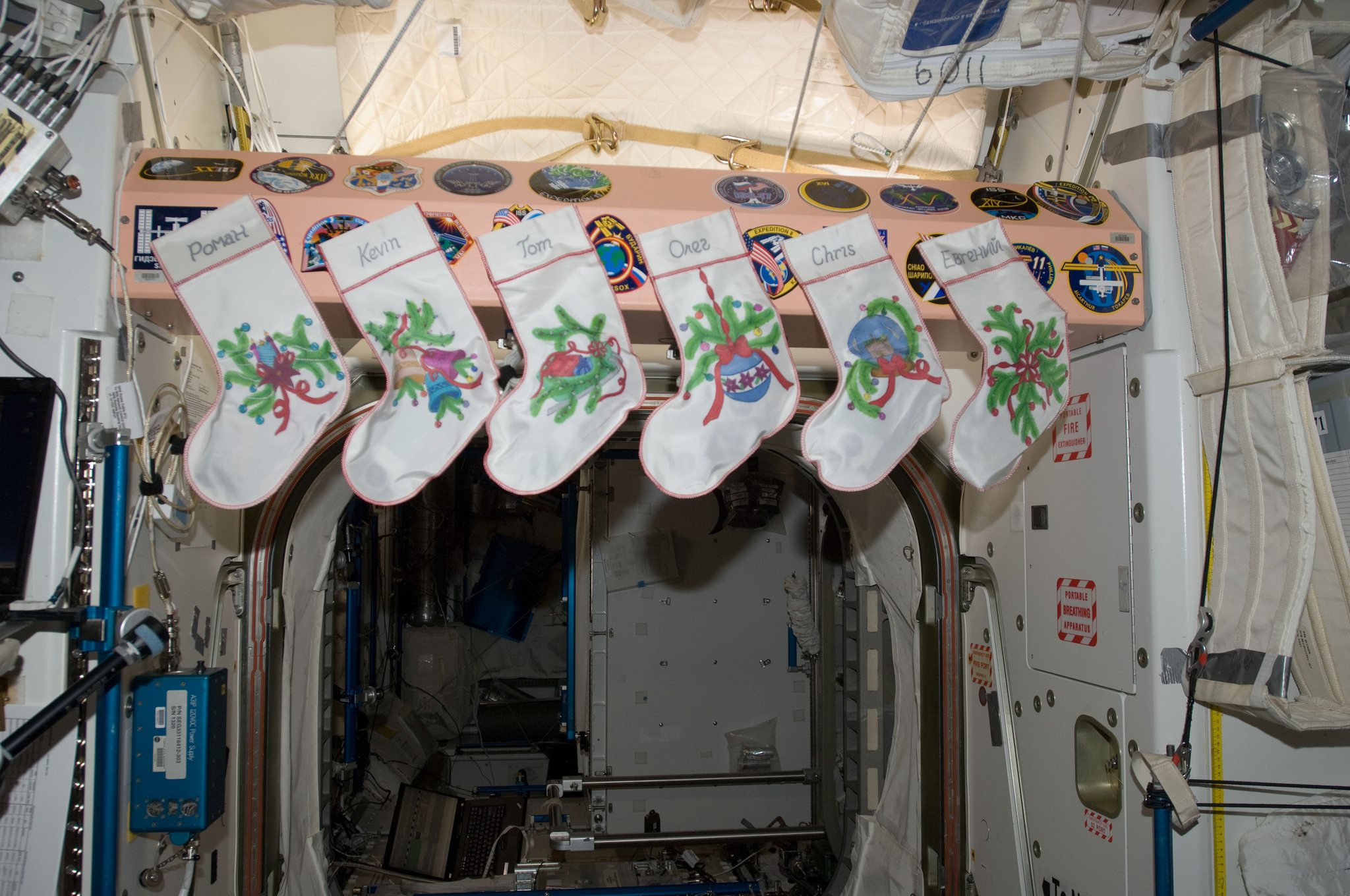 With a fire unavailable, the Christmas stockings of consecutive International Space Station (ISS) crews have been hung by the hatch. With care, of course. Photo Credit: NASA